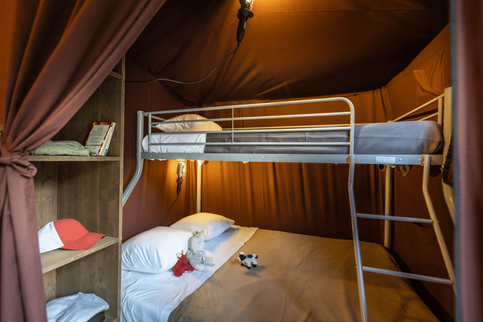 Interieur van een glamping tent in Arizona met stapelbed, sfeerverlichting en een open kast.