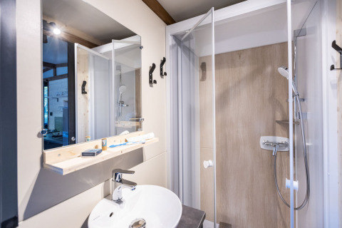 Salle de bains moderne avec douche, miroir et lavabo dans l’hébergement glamping Arizona, ambiance claire.