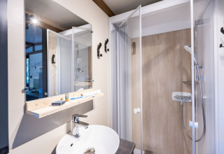 Salle de bains moderne avec douche, miroir et lavabo dans l’hébergement glamping Arizona, ambiance claire.