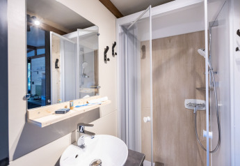 Moderne badeværelse med bruser, spejl og håndvask i glampingboligen Arizona, lyst og funktionelt.