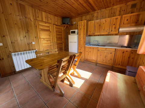Cocina y comedor con paneles de madera en Chalet Bois, Huttopia Barcelona Pirineos, España.