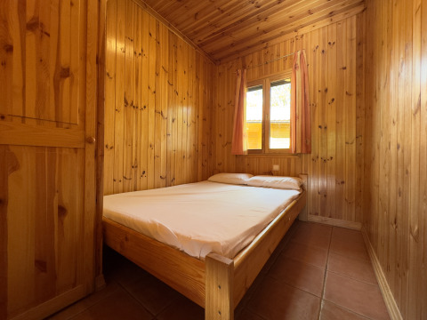 Soveværelse med dobbeltseng i træbeklædt chalet på Chalet Bois, Huttopia Barcelona Pirineos, Spanien.