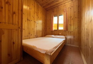 Soveværelse med dobbeltseng i træbeklædt chalet på Chalet Bois, Huttopia Barcelona Pirineos, Spanien.