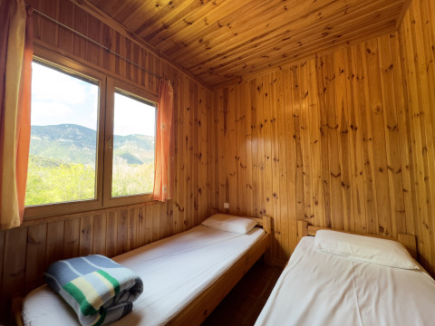 Two single beds in a cozy wood-paneled room at Chalet Bois, Huttopia Barcelona Pirineos, Spain.