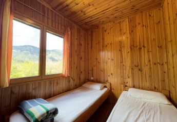 Two single beds in a cozy wood-paneled room at Chalet Bois, Huttopia Barcelona Pirineos, Spain.