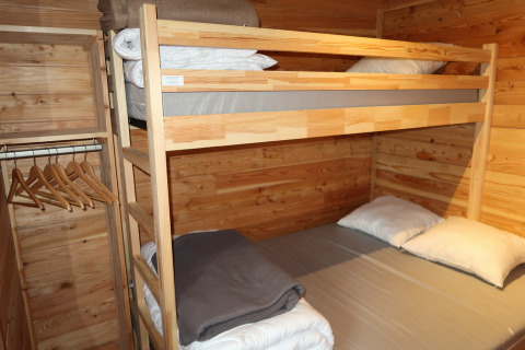 Stapelbed en kledingkast in een houten kamer bij Montana Chalet Vista, Huttopia Barcelona Pirineos, Spanje.