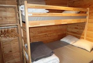 Bunk bed and wardrobe in wood-paneled room at Montana Chalet Vista, Huttopia Barcelona Pirineos, Spain.