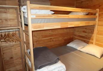 Køjeseng og garderobe i træværelse på Montana Chalet Vista, Huttopia Barcelona Pirineos, Spanien.