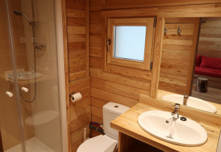 Badkamer in Montana Chalet Vista bij Huttopia Barcelona Pirineos, Spanje, met houten interieur en douche.