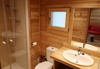 Badkamer in Montana Chalet Vista bij Huttopia Barcelona Pirineos, Spanje, met houten interieur en douche.