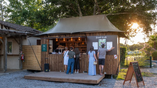Food truck at Huttopia Lac d'Aureilhan - Mimizan holiday park in France, with people and sunset scenery.