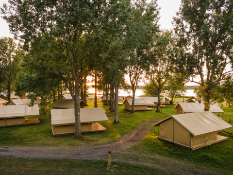 Solopgang over safari-telte i træomgivelser på Classic Tent ved Huttopia Lac d'Aureilhan - Mimizan i Frankrig.