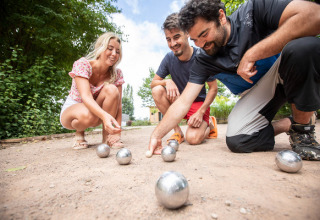Drie mensen spelen jeu de boules buiten op grind bij Huttopia Lac d'Aureilhan vakantiepark in Frankrijk.