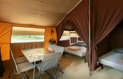 Vue intérieure d'une tente safari Classic à Huttopia Lac d'Aureilhan, avec table et lits, en France.