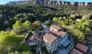 Luftaufnahme von Gebäuden und grüner Landschaft nahe Felsklippen bei Guardiola de Berguedà, Spanien.