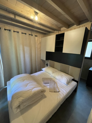 Slaapkamer van een tiny house, Ecolodge, bij Hameau de l’Ourthe in België, met knusse moderne sfeer.