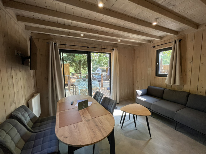 Moderne tiny house Ecolodge in Hameau de l'Ourthe, België, met houten interieur, zetel en terras.
