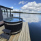 Uitzicht vanaf Houseboat Marina Mookerplas met een hottub op het dek aan het meer onder blauwe lucht.