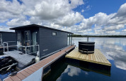 Hausboot bei der Marina Mookerplas in den Niederlanden mit privatem Whirlpool auf hölzernem Deck.