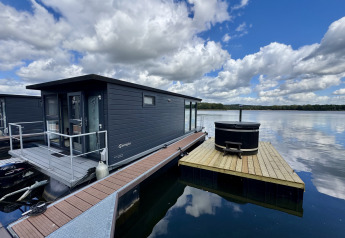 Flydende husbåd ved Marina Mookerplas i Holland med træterrasse og udendørs hottub på søen.