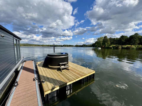Péniche à la Marina Mookerplas, Pays-Bas, avec jacuzzi sur terrasse en bois surplombant le lac paisible.