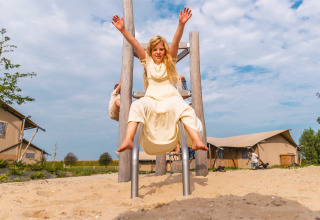 A joyful girl in a light dress slides down a playground slide at Vakantiepark IJsselhof holiday park.