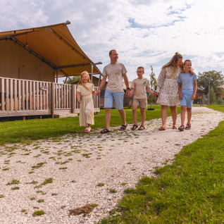 Gezin wandelt op een pad aan tenten bij Vakantiepark IJsselhof, een vakantiepark in Noord-Holland, Nederland.