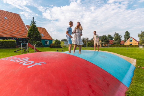 Family bouncing and playing on a large colorful air trampoline at Vakantiepark IJsselhof in North Holland.