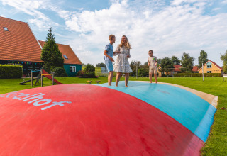 Family bouncing and playing on a large colorful air trampoline at Vakantiepark IJsselhof in North Holland.