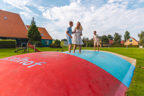 Famille s'amusant sur un grand coussin sauteur coloré à Vakantiepark IJsselhof, en Hollande-Septentrionale.