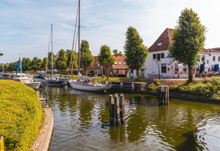 Bateaux amarrés sur un canal près du parc IJsselhof, entourés d'arbres et de maisons en Hollande-Septentrionale.