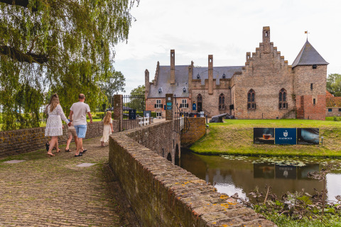 Family walks across a stone bridge toward a historic castle at Vakantiepark IJsselhof in North Holland, Netherlands.