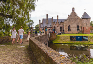 Familie spaziert über eine Brücke zu einer Burg nahe dem Vakantiepark IJsselhof in Nordholland, Niederlande.