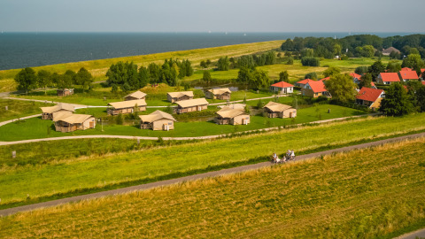 Luftfoto af ferieparken IJsselhof i Nordholland med hytter, græsarealer og udsigt over havet.