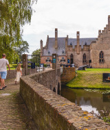 Gezin loopt over brug naar historisch kasteel met gracht in de buurt van Andijk, Noord-Holland, Nederland.