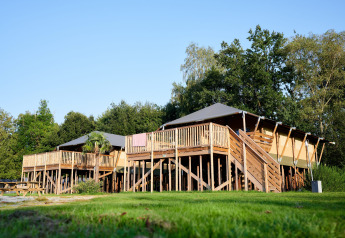 Safari Boomhut avec sanitaires au Camping Goorzicht aux Pays-Bas, maison sur pilotis entourée de verdure.
