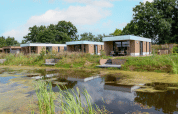Modern water lodge with hot tub at Hofparken Wiltershaar in the Netherlands, surrounded by a pond and nature.