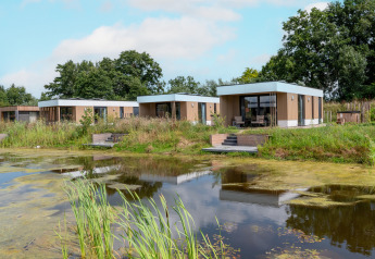 Modern water lodge with hot tub at Hofparken Wiltershaar in the Netherlands, surrounded by a pond and nature.