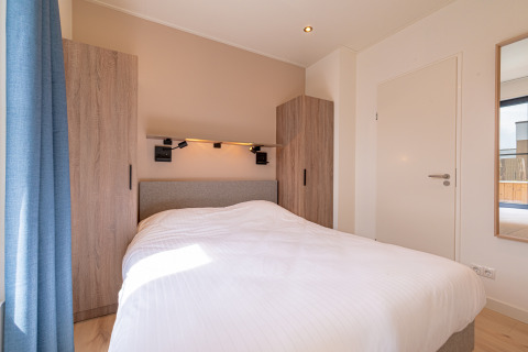 Slaapkamer van Water lodge 2 met wit beddengoed en modern interieur in Hofparken Wiltershaar, Nederland.