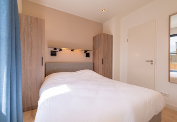 Bedroom inside Water lodge 2 with white bedding and a modern interior at Hofparken Wiltershaar, Netherlands.