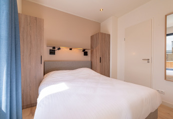 Slaapkamer in Water lodge 2 met wit beddengoed en modern interieur bij Hofparken Wiltershaar, Nederland.