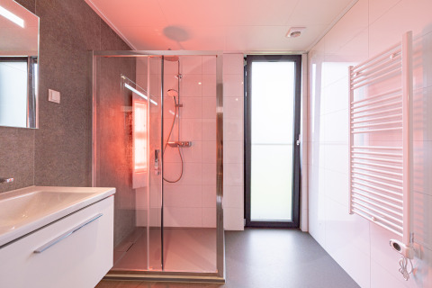 Salle de bain moderne avec douche, lavabo, grande porte vitrée et radiateur sèche-serviettes à Water lodge 2 Deluxe
