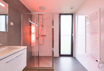 Salle de bain moderne avec douche, lavabo, grande porte vitrée et radiateur sèche-serviettes à Water lodge 2 Deluxe