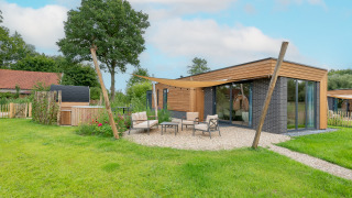 Moderne Lodge mit Holzverkleidung, großen Fenstern und gemütlichem Sitzbereich im Garten.