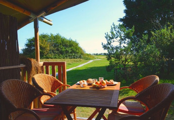 Colazione su una terrazza in tenda safari al Parc Koudenburg, Paesi Bassi, vista su natura verde.