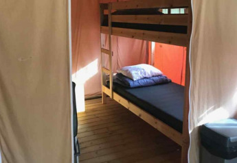 Interior of a safari tent with bunk bed, wooden floor and basic furnishings at Parc Koudenburg, Netherlands.