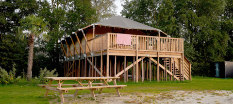 Cabane Safari Boomhut sur pilotis avec balcon et table de pique-nique au Camping Goorzicht, Pays-Bas, nature.