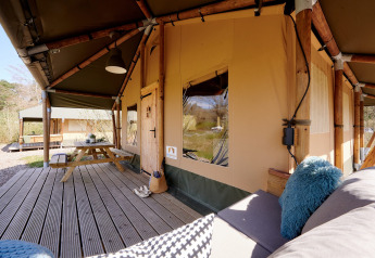 Veranda van Safari Boomhut met zitbank en tafel bij Camping Goorzicht in Nederland.