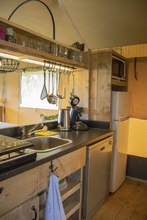 Cucina completamente attrezzata con lavastoviglie, frigorifero e microonde in una casa sull’albero safari a Goorzicht.