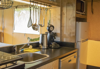 Cucina completamente attrezzata con lavastoviglie, frigorifero e microonde in una casa sull’albero safari a Goorzicht.